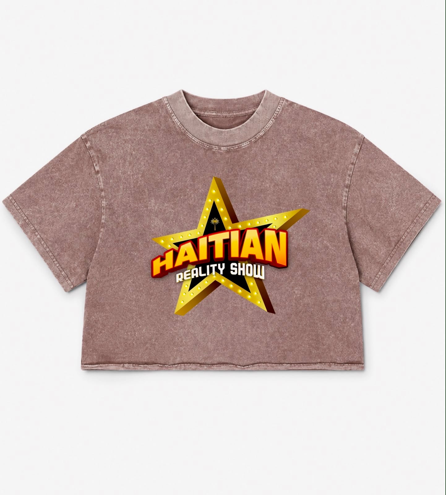 A cropped short-sleeve t-shirt in a washed, mineral-washed brownish-pink color, featuring a large graphic on the front with a gold star and the text 'HAITIAN REALITY SHOW'.